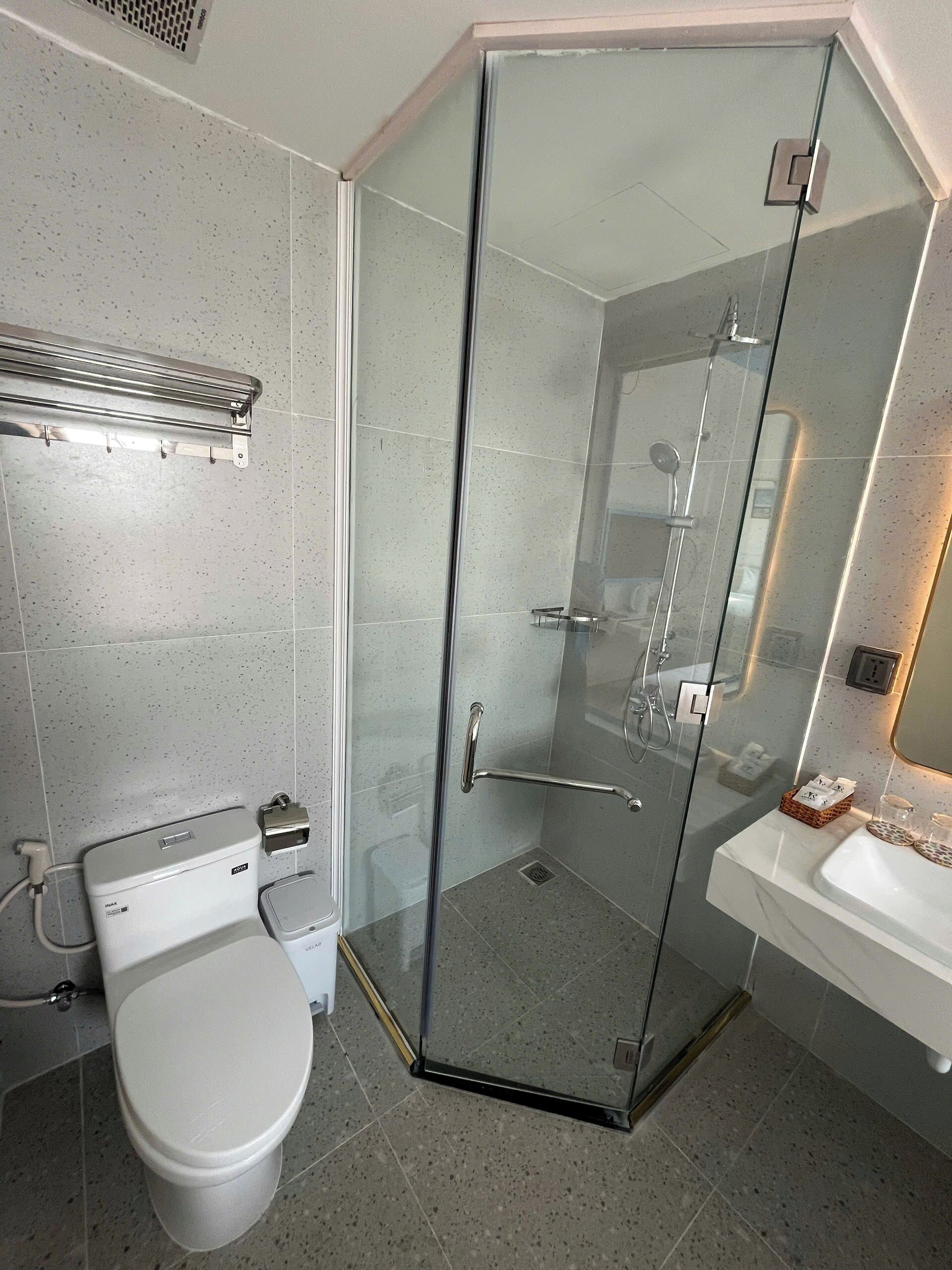 Un baño moderno con ducha de mampara de vidrio, inodoro y lavamanos.
