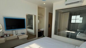 Habitación de hotel con cama, televisor, espejo, armario y aire acondicionado.