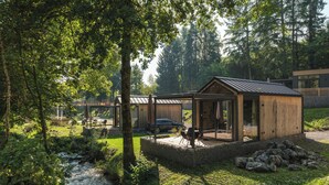 A modern cabin with a glass door, surrounded by a natural forest setting.