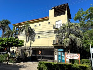 A multi-story building with a balcony, a sign indicating 'Condominios Horizontes del Mar,' and a gated entrance. - Ground floor Condo Steps from the Sand with Pool and Sunset Views (Playa Langosta)