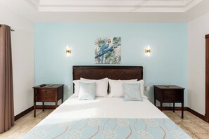 Ein Schlafzimmer mit einem großen Bett, zwei Nachttischen, einem Kopfteil mit einem Gemälde und Wandleuchten.