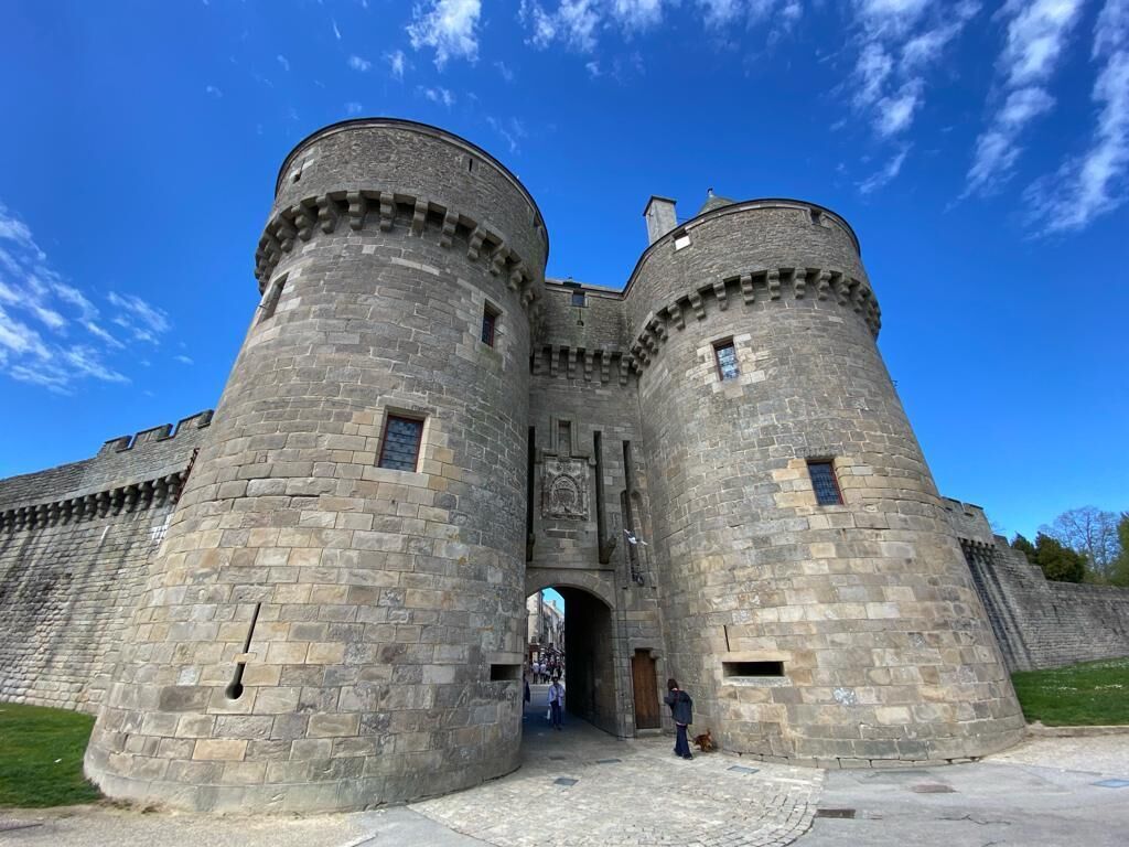 A historic stone castle with two round towers, a central entrance, and a paved courtyard.