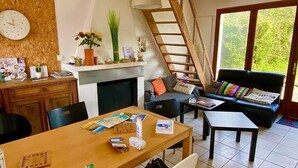 Een woonkamer met een open haard, een eethoek, een bank en een trap.