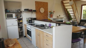 Een kleine keuken met een magnetron, fornuis, spoelbak en houten kastjes.