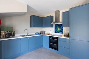 Eine moderne Küche mit blauen Schränken, einer Edelstahl-Spüle und einem eingebauten Backofen.