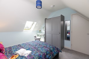 Ein Schlafzimmer mit Bett, Kleiderschrank, Schreibtisch und Fenster.