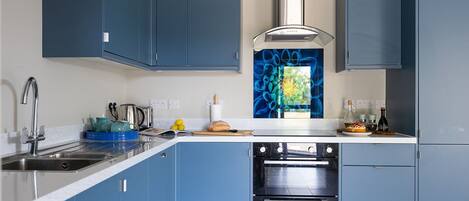 Une cuisine moderne avec des armoires bleues, des appareils en acier inoxydable et un crédence décorative.