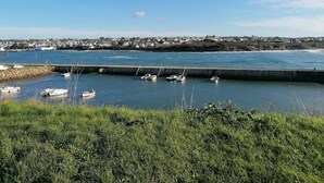 Vista costera con un puerto deportivo, barcos y un pueblo lejano.