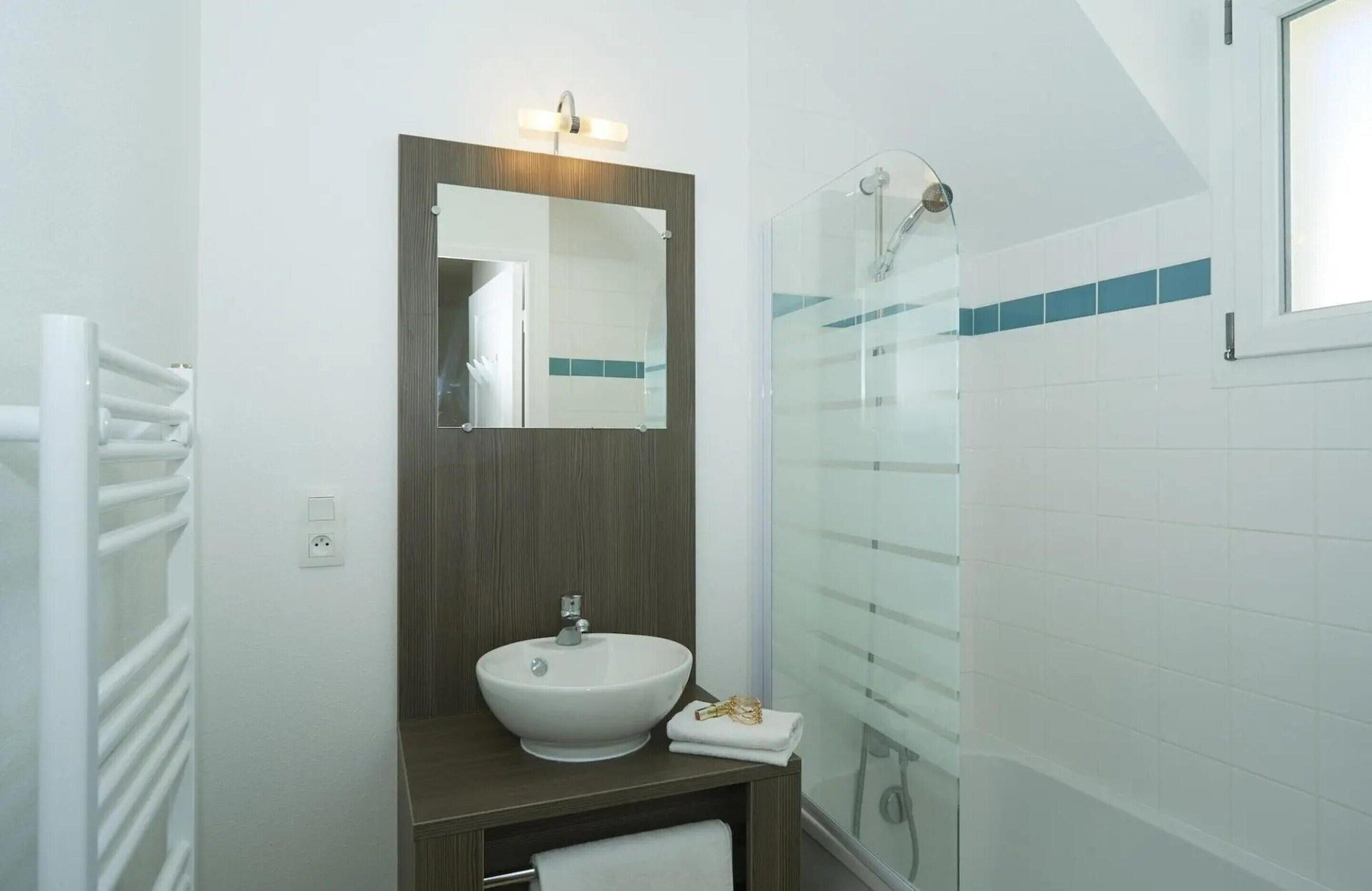 Un bagno moderno con lavandino bianco, specchio e cabina doccia in vetro.