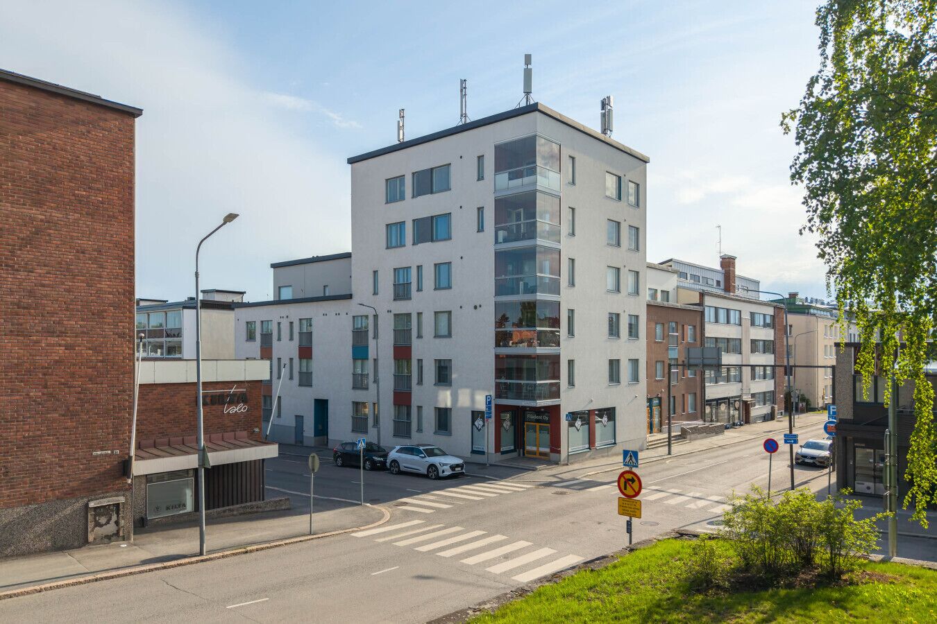 Een meerlaags gebouw met een modern ontwerp, met een combinatie van glazen en bakstenen gevels, en een zichtbare ingang met een bord.