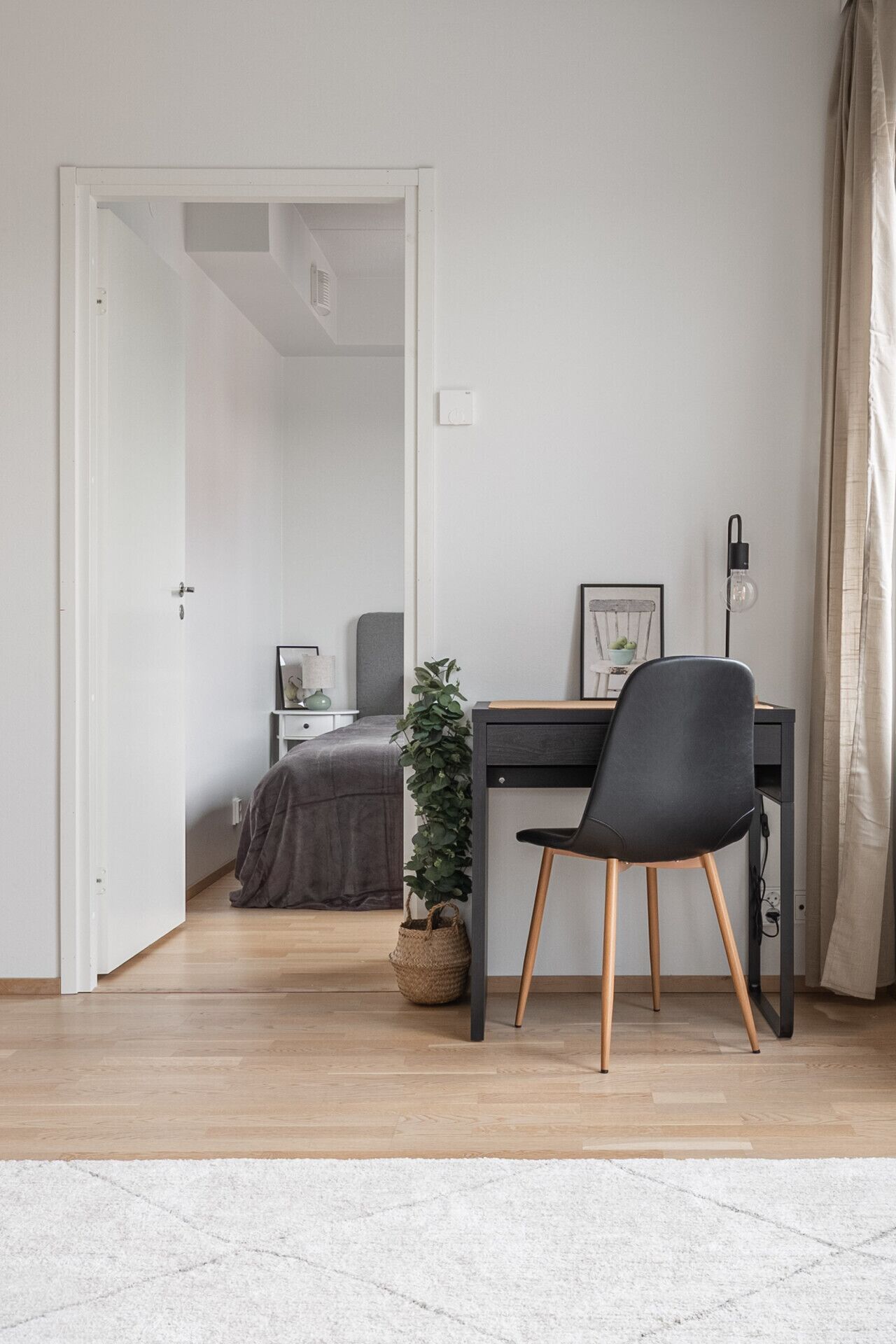 Une chambre à coucher avec un lit, une table de chevet, une lampe et une petite plante en pot.