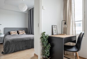 A modern bedroom with a bed, bedside table, and a desk with a chair.