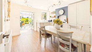 Una cocina moderna con comedor, un reloj y vistas al exterior.