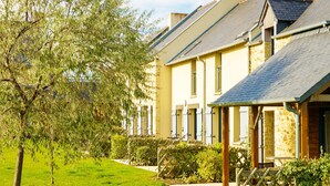 A row of traditional houses with stone facades, a grassy lawn, and a tree. - Charming Breton Duplex Cottage (Cancale)