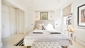 Une chambre spacieuse avec un grand lit, une table de chevet avec une lampe et une fenêtre donnant sur un beau paysage.