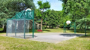 Une aire de jeux équipée d’un panier de basket et d’une structure d’escalade en forme de filet.