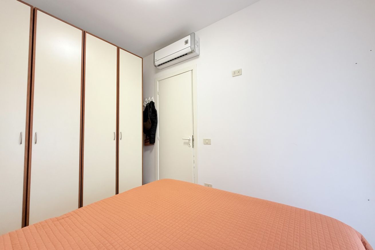 A bedroom with a bed, a wardrobe, and an air conditioning unit.