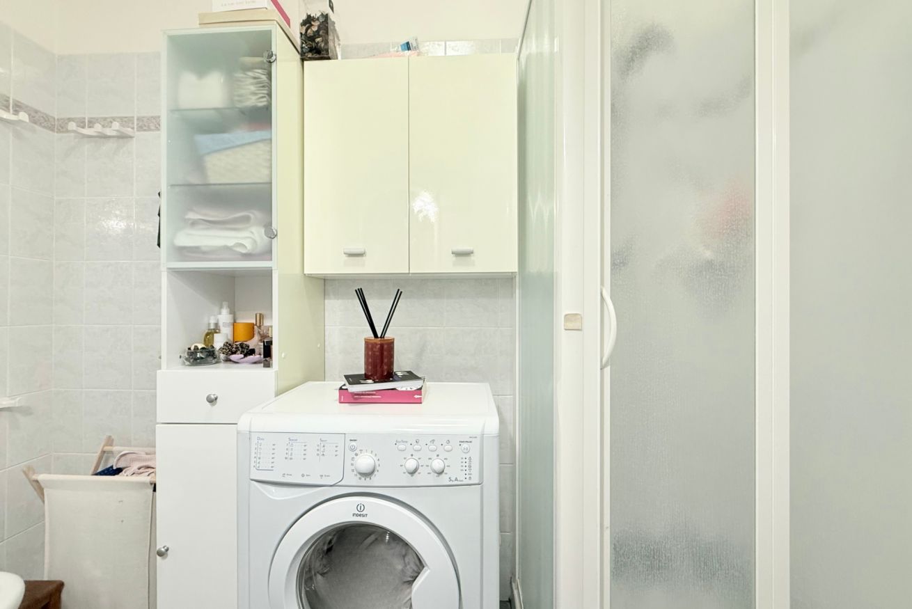 A laundry area with a washing machine, a cabinet with toiletries, and a towel rack.