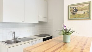 A kitchen with white cabinets, a sink, a dishwasher, a wooden countertop, and a potted plant.