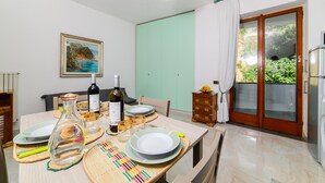 Un'area pranzo con un tavolo apparecchiato per quattro persone, una bottiglia di vino e un quadro appeso al muro.