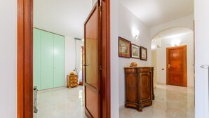 Un corridoio con una porta in legno, un armadio verde, un mobiletto in legno e un pavimento piastrellato.