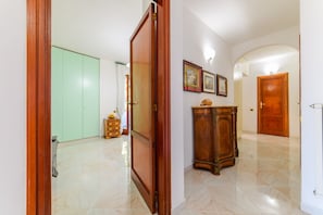 A hallway with a wooden door, a green wardrobe, a wooden cabinet, and a tiled floor. - Casa Cinzia (Vico Equense)