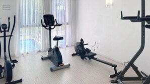 Un gimnasio con máquinas de cardio, una bicicleta estática y una máquina de remo.