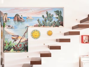 A staircase with a painting of a coastal scene and two sun decorations.