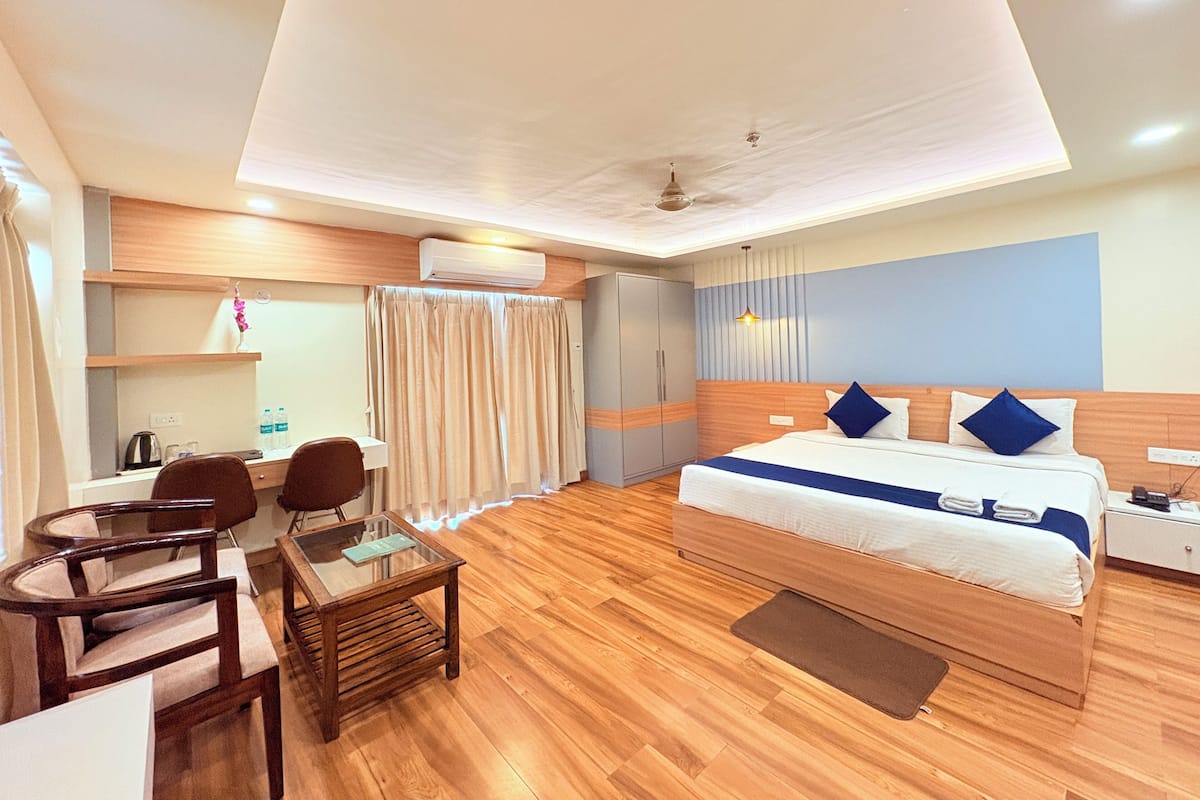 Una habitación de hotel con una cama, un escritorio con sillas, un armario y un ventilador de techo.