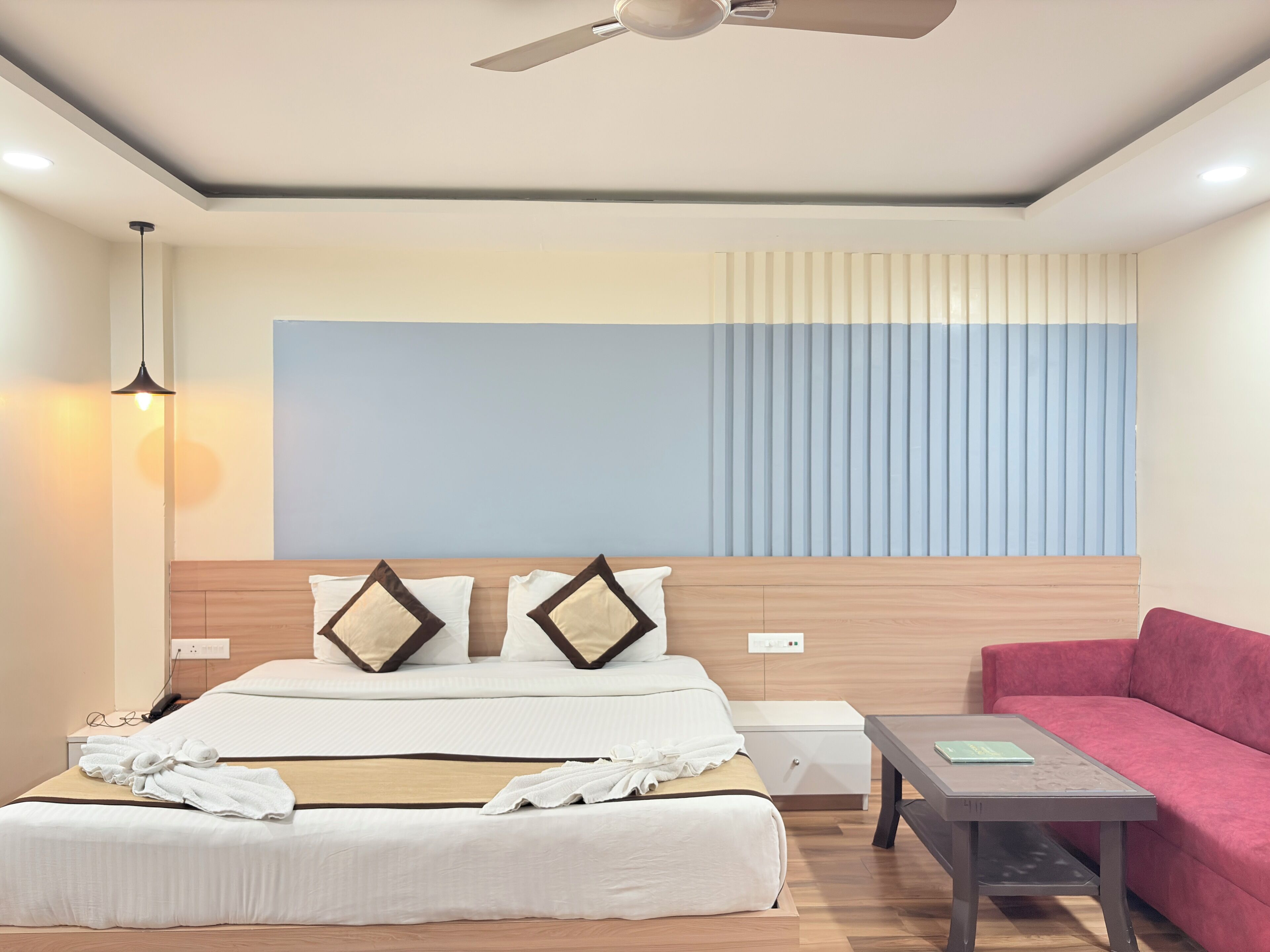 A hotel room with a bed, bedside table, and a red sofa.