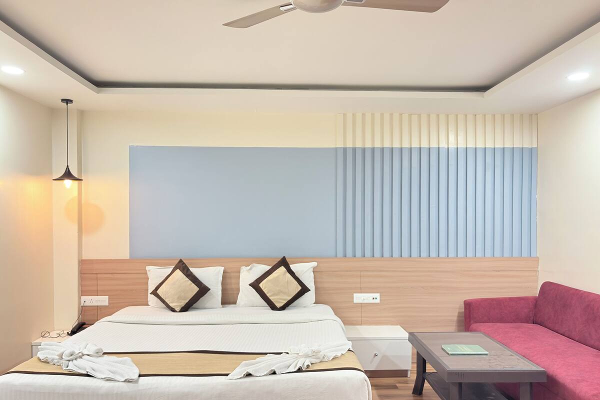Una habitación de hotel con cama, mesita de noche y sofá rojo.