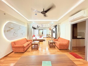 A modern living room with a ceiling fan, two sofas, a coffee table, and a wooden floor. - Durene Beach New Marine Drive road (Brahmagiri)