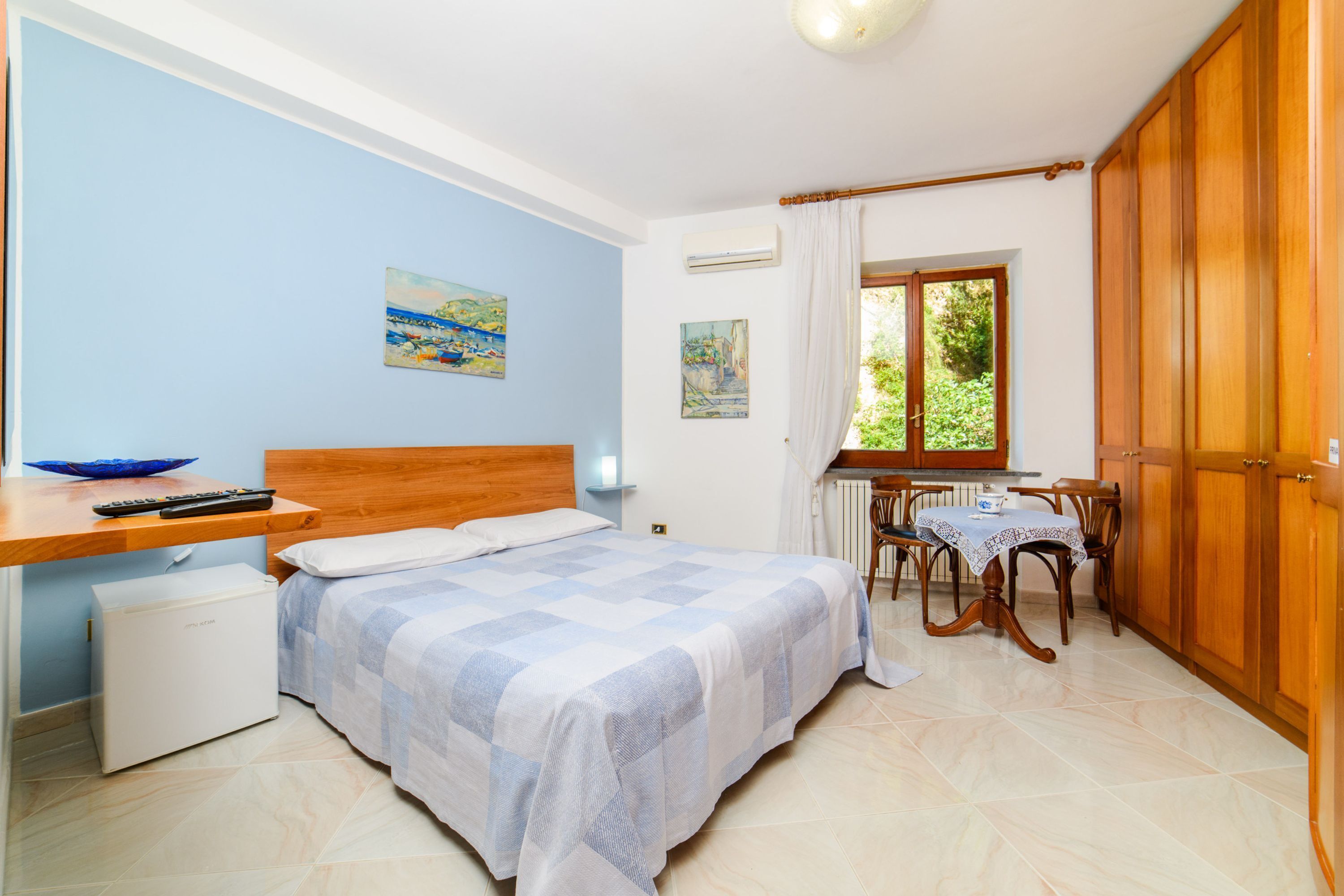 Een slaapkamer met een bed, een bureau, een stoel en een raam.