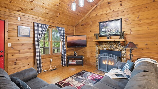 Ein gemütliches Blockhaus-Interieur mit Kamin, Fernseher und einer bequemen Sitzecke.