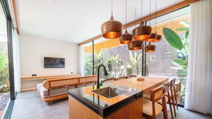 Cozinha moderna com ilha central, mobiliário de madeira e grandes janelas com plantas.