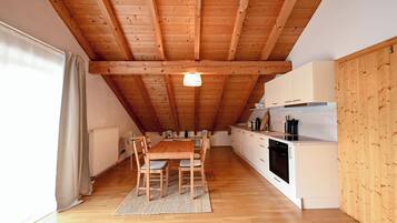 A kitchen with wooden beams, a dining table with chairs, and white cabinets.