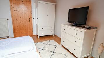 A bedroom with a bed, a TV, a white wardrobe, and a wooden door.