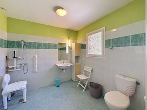 Ein Badezimmer mit Toilette, Waschbecken, Dusche und einem Stuhl.