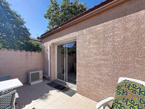Eine Terrasse mit Tisch und Stühlen, eine Glastür zum Verschieben und eine strukturierte Wand.