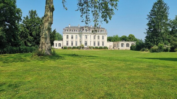 A large, classical building with a symmetrical facade, surrounded by a well-maintained lawn and mature trees. - Gîte with pets allowed - 14 guests (Roucourt)