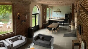 A spacious living area with a sofa, a dining table, and a kitchen in the background. - Gîte with pets allowed - 14 guests (Roucourt)