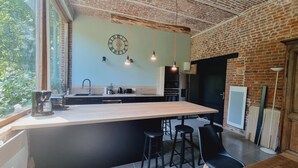 A modern kitchen with a large island, black bar stools, and hanging pendant lights. - Gîte with pets allowed - 14 guests (Roucourt)