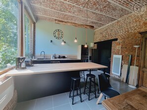 Una cocina moderna con una isla grande, taburetes negros tipo barra y lámparas colgantes.