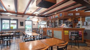 A restaurant interior with tiled floors, wooden tables and chairs, a counter with various items, and a view through the window. - Cozy mobile home with terrace - 4 guests (Dossenheim-sur-Zinsel)