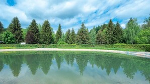 A serene outdoor pool with a wooden deck, surrounded by dense trees and a clear sky. - Cozy mobile home with terrace - 4 guests (Dossenheim-sur-Zinsel)