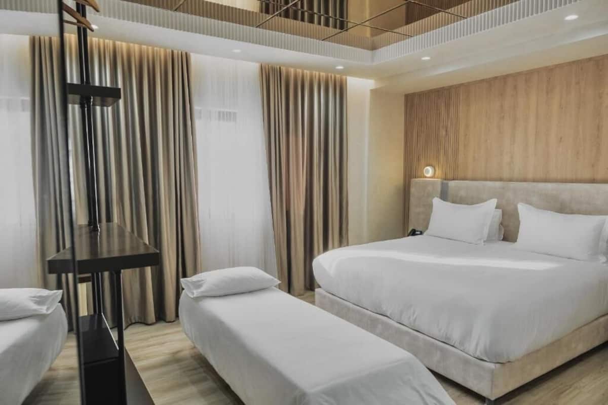 Habitación de hotel con una cama grande, una mesita de noche, un banco y una pared decorativa de madera.