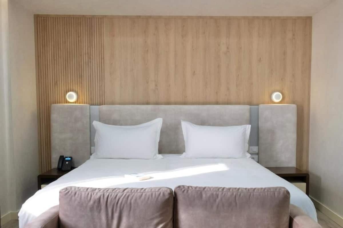 Una habitación de hotel con una cama grande, dos mesitas de noche y un cabecero de madera.