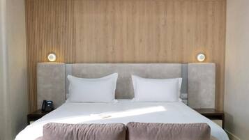 A hotel room with a large bed, two bedside tables, and a wooden headboard.