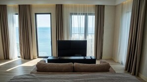 Une chambre avec un lit, une télévision et une vue sur la mer.
