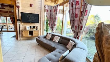 Ein Holzinnenraum mit einer Couch, einem Fernseher und Vorhängen.